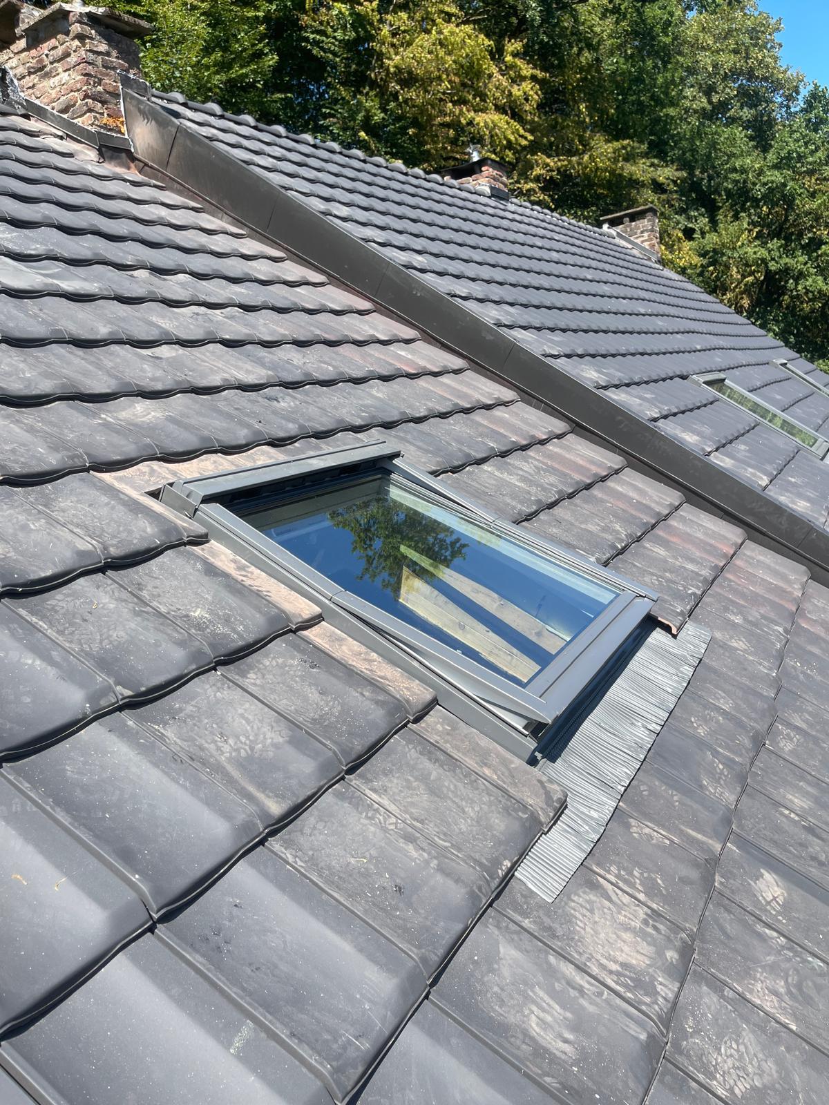 Fenêtre de toit posée dans une couverture en tuiles anthracite, avec arêtier en zinc